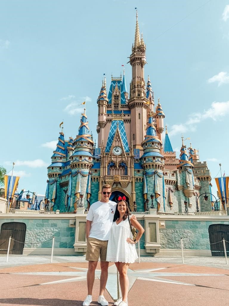 Couple standing in front of Disney World Cinderella's Castle on a sunny day
