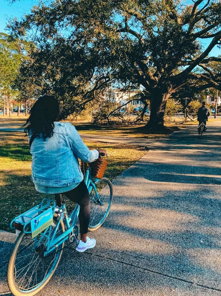 Back view of girl biking through a park 