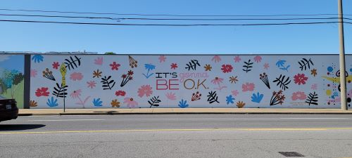 Wide mural with white background and colorful flowers that reads 