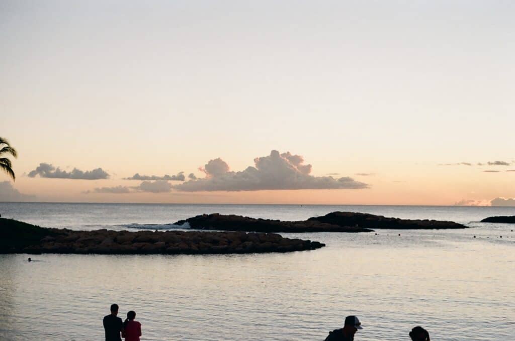 Sunset in ko olina area of oahu with ocean and people on a beach