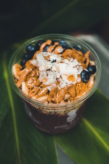 Acai bowl topped with granola, coconut, peanut butter, and blueberries