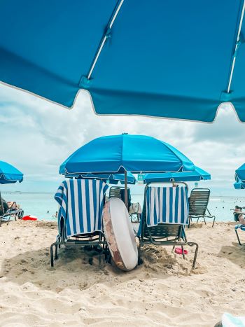 Two beach chairs with blue umbrella and floatie