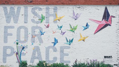 Mural that reads wish for peace in large block letters on the left side. On the right side are colorful origami swans