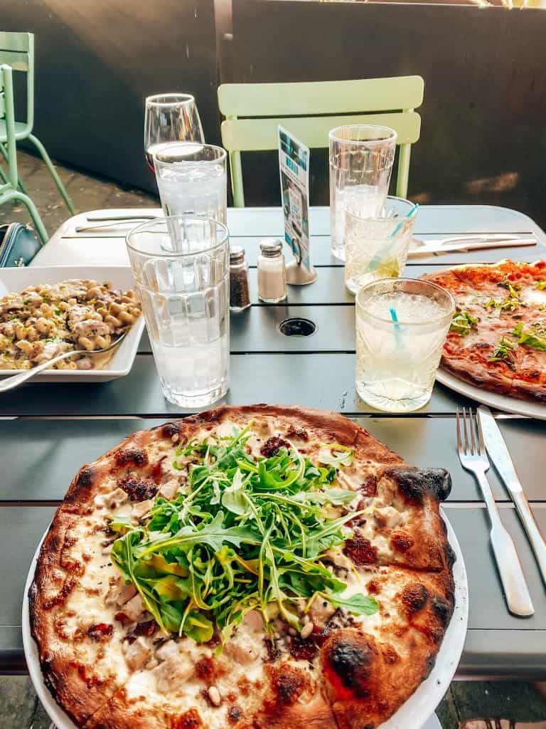 Table with two pizzas and a bowl of pasta at the liberty market in downtown gilbert 