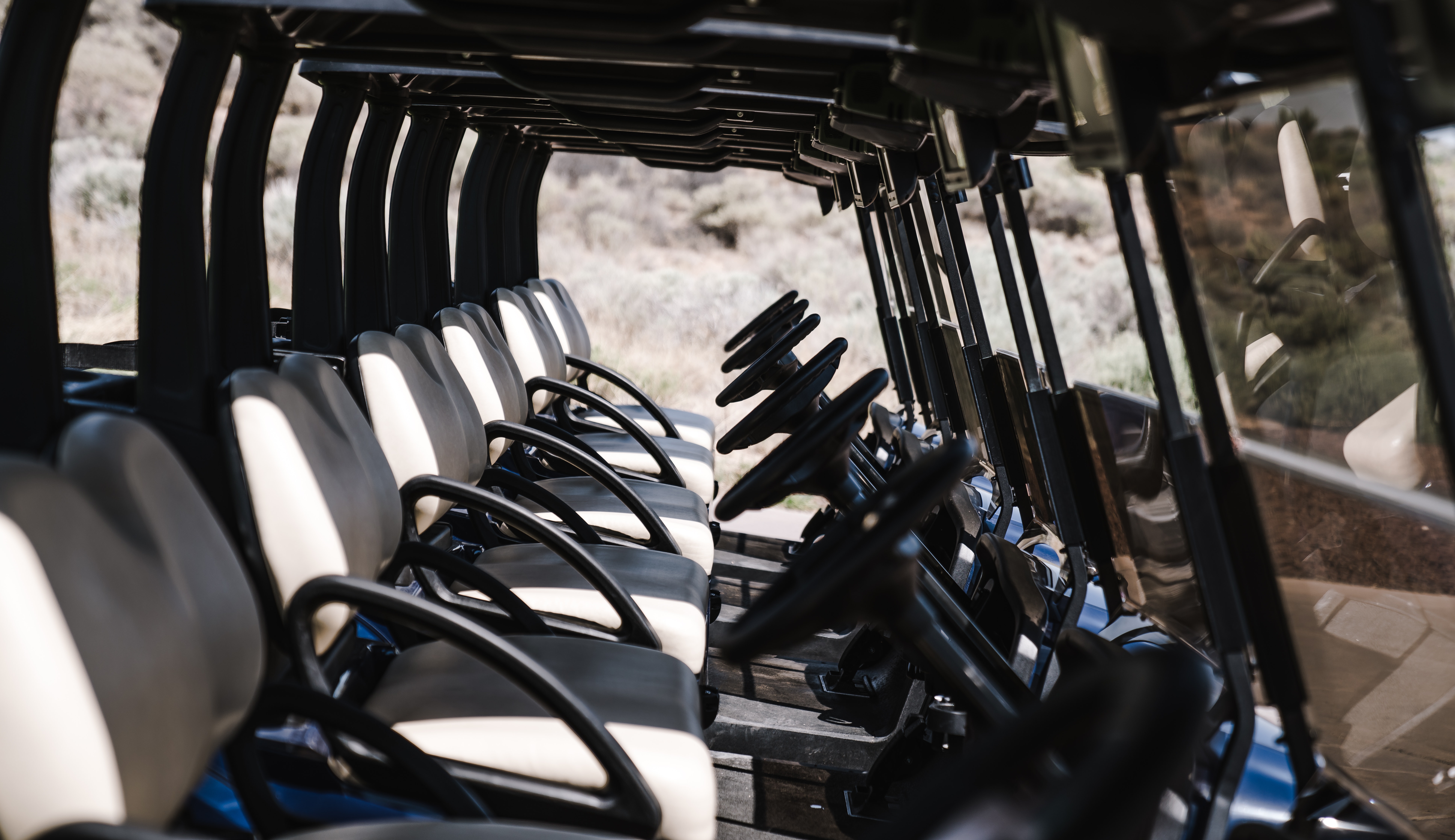 Shot through ATVs lined up with view of the seats and steering wheels
