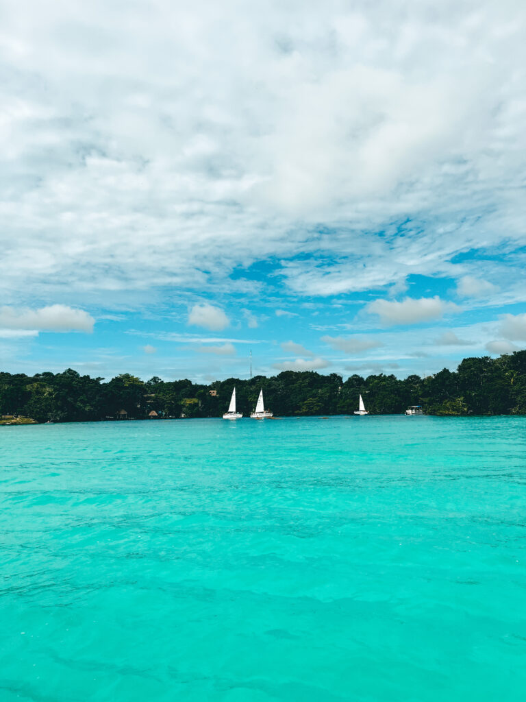 Bright blue water of bacalar lagoon with sail boats in distance
