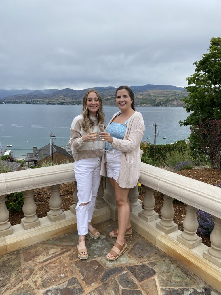 Two girls holding wine glasses with lake in background