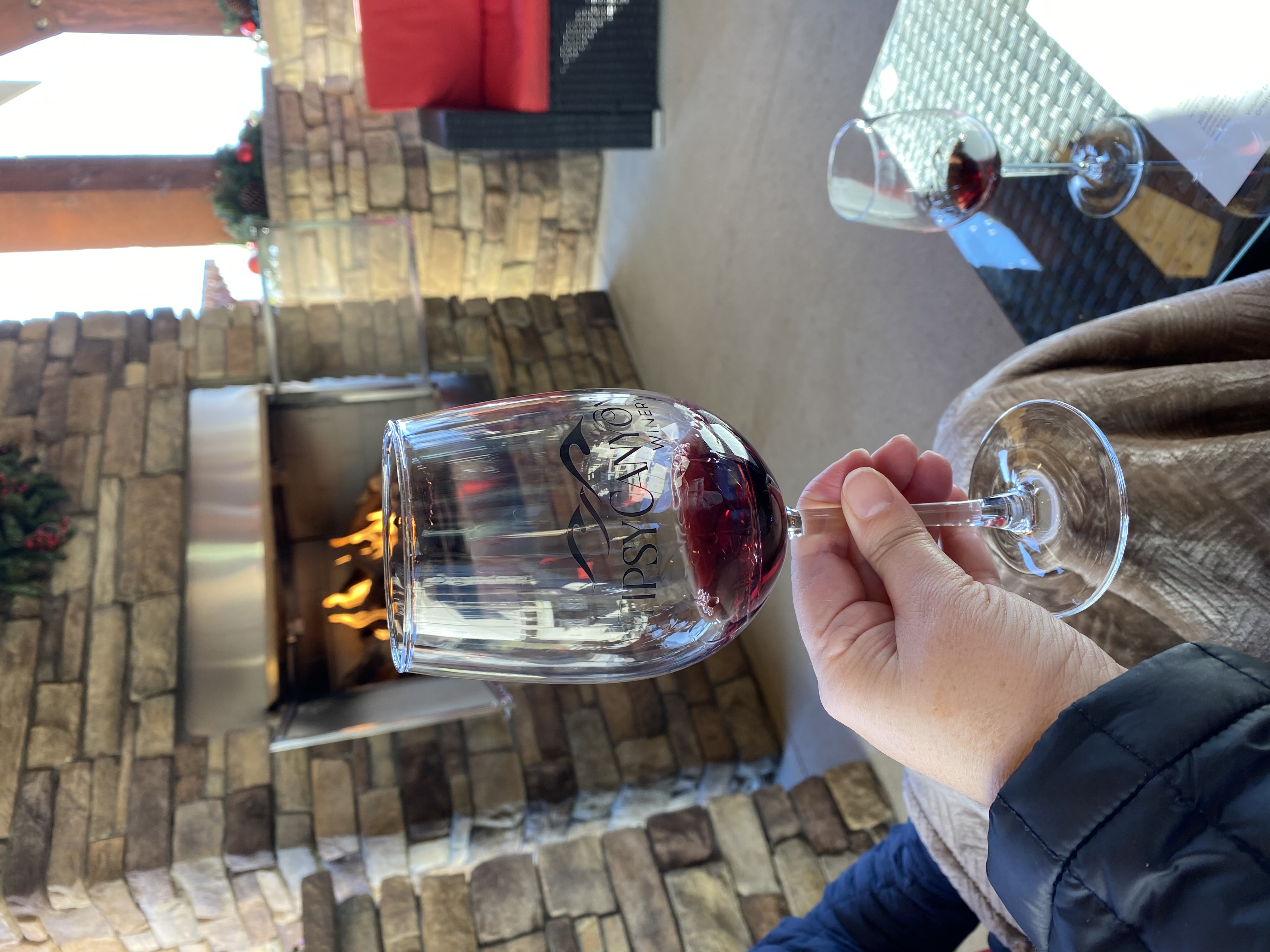 Wine glass with red wine and stone fireplace in background