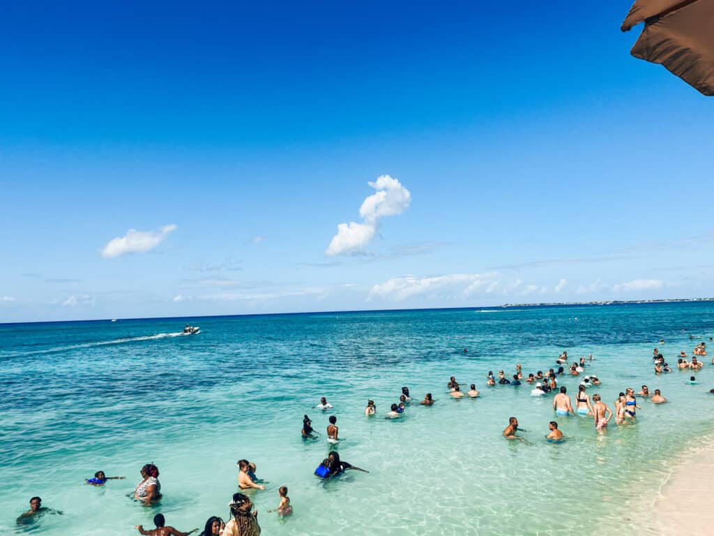 people swimming in the blue water at seven mile beach in grand cayman