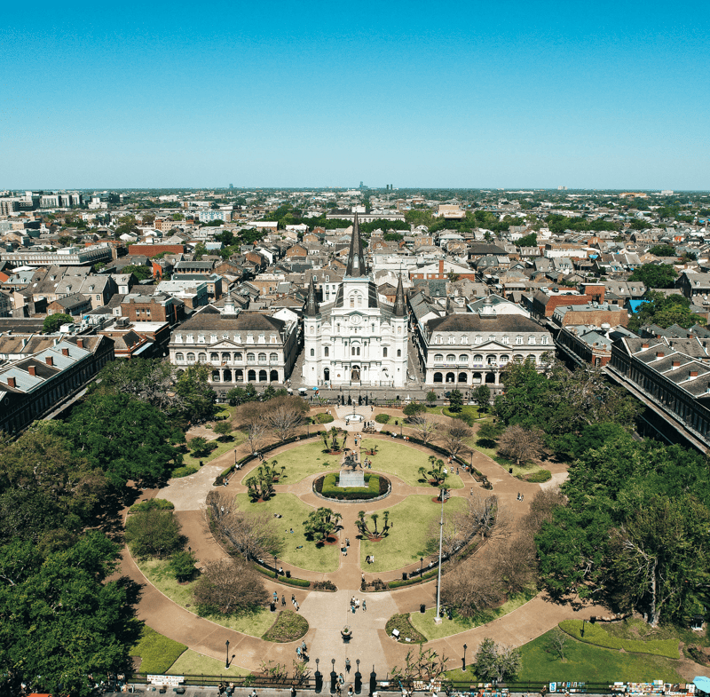 Aerial view of Jackson Square with the iconic St. Louis Cathedral in the heart of the French Quarter, New Orleans, surrounded by historic buildings and lush greenery.