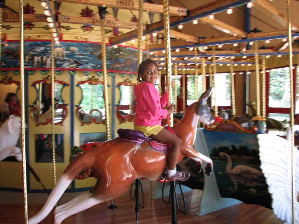 Young girl riding on a a gold colored carousel 