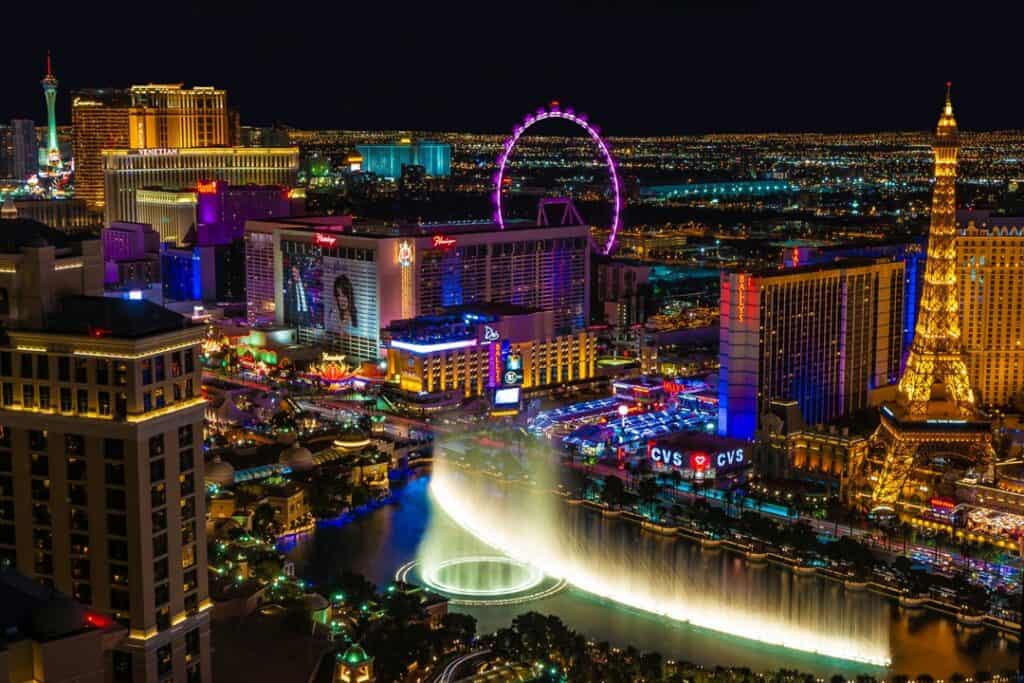 Nighttime dazzles in Las Vegas, Nevada, with the vibrant lights of the Strip highlighting famous landmarks, including the High Roller Ferris wheel and the Eiffel Tower replica, alongside the spectacular Bellagio fountain show.