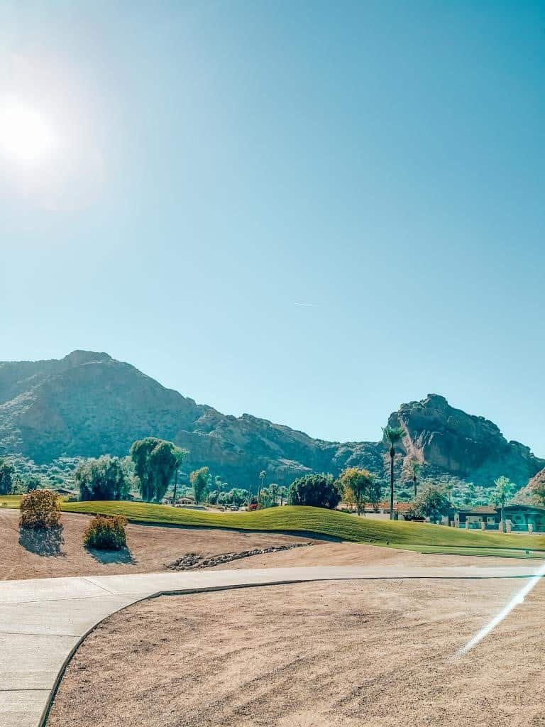 Sunny day at Camelback Mountain with a clear sky, featuring the golf course's manicured greenery and sand traps, providing golfers with a picturesque and challenging desert landscape to enjoy