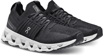 A pair of black On Cloudswift running shoes with a white sole and the brand's logo on the side. The design features a unique lacing structure and cushioned CloudTec outsole for a blend of style and performance.