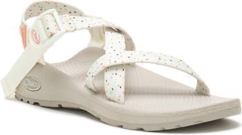 White Chaco sandals with polka dot patterned straps and the Chaco logo on the adjustable buckle.