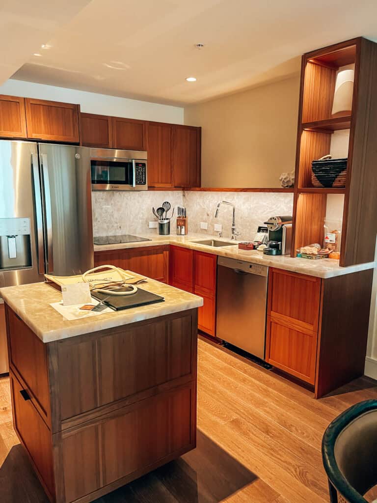 The second image captures a well-appointed kitchen with warm wood cabinetry, stainless steel appliances, and a marble-topped island. The space is inviting, with thoughtful touches like organized cooking utensils and a coffee station.