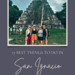 A group of friends stands in front of an ancient stone temple, posing for a photo at Tikal, Guatemala, under cloudy skies. The image is framed within a purple graphic titled "17 Best Things to Do in San Ignacio, Belize," hinting at travel recommendations by TheTravelingMoore.com. The backdrop of lush greenery and historic ruins adds an adventurous feel to the visual.