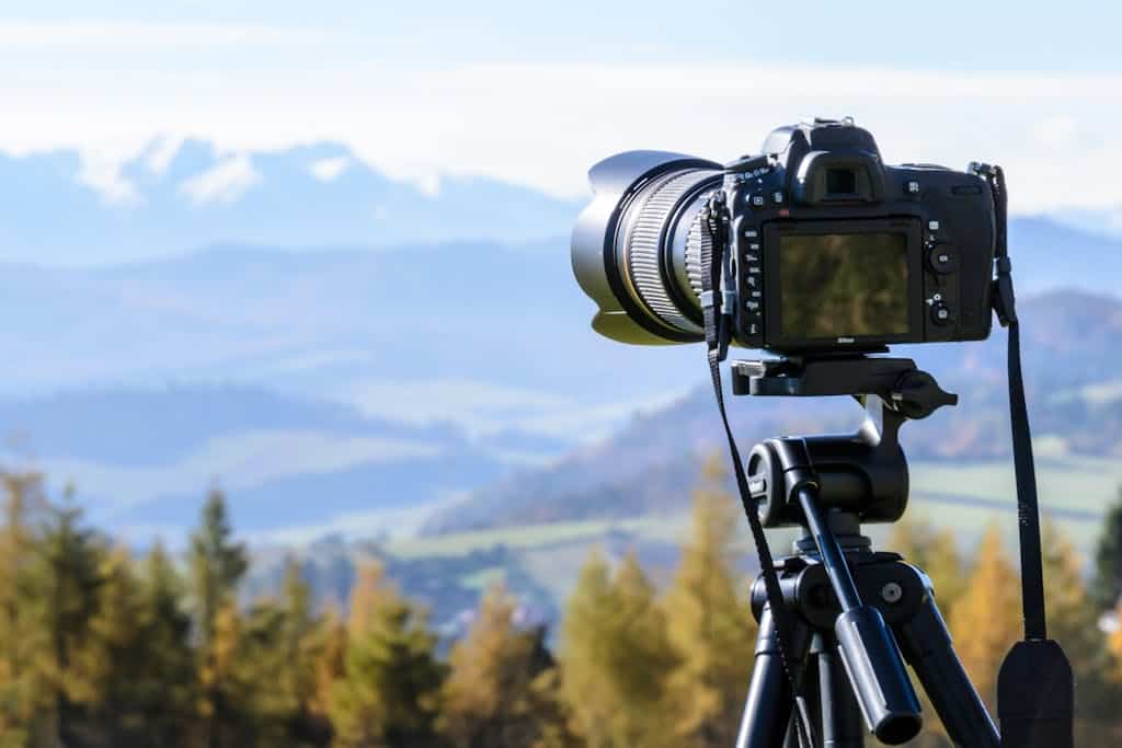 DSLR camera on tripod capturing a stunning mountain view on a clear day.