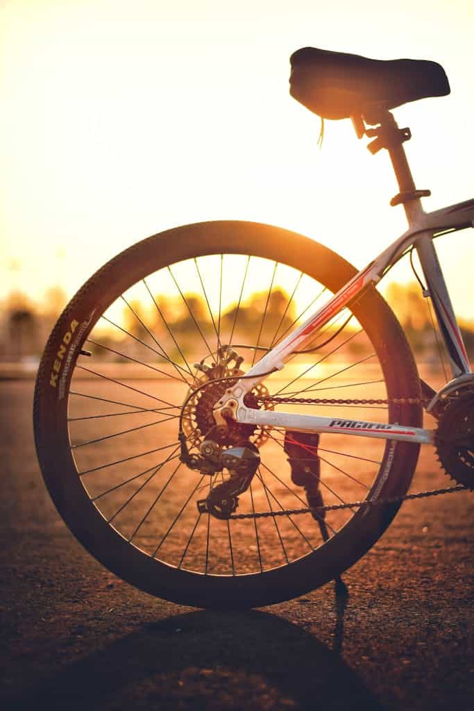 Silhouetted bicycle wheel captured with sunset backdrop, highlighting gears and frame.